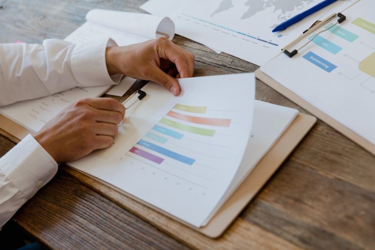 O que o estoque de CPR revela sobre as opções de crédito no campo Mãos analisam um relatório financeiro com gráficos coloridos sobre uma mesa de madeira.